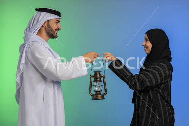 الاستعداد لقدوم رمضان, استقبال شهر الخير والبركة, المناسبة الدينية والعيد الإسلامي, بورتريه لرجل عربي خليجي اماراتي يرتدي الكندورة و الغترة التقليدية يقدم الفانوس لزوجته, تحف وزينة الاحتفالات في الامارات, خلفية ملونة