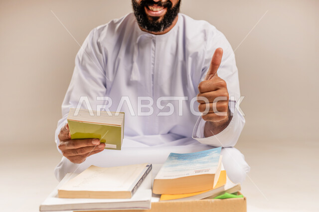 مبادرة انسانية في سلطنة عمان، مفهوم المساعدة والتبرع، توفير المؤلفات التعليمية للمحتاجين، بورتريه لرجل عربي خليجي عماني مبتسم يرتدي الدشداشة يقوم بتجهيز صندوق تبرعات من الكتب الفائضة يرفع إصبع الإبهام بإيماءات القبول والإعجاب، علامة الجودة والامتياز، خلفية بيج