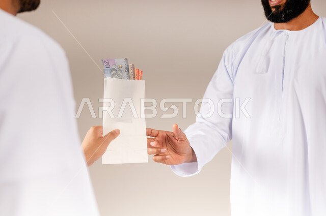 التقرب إلى الله بالعطاء والصدقة، جمعية خيرية ومبادرة إنسانية في سلطنة عمان، مفهوم المساعدة والتبرع، بورتريه مقرب لرجل عربي خليجي عماني يرتدي الدشداشة يحمل بيده ظرف من النقود الورقية يقوم بتقديمه لشخص آخر، إخراج زكاة المال للمحتاجين، خلفية بيج