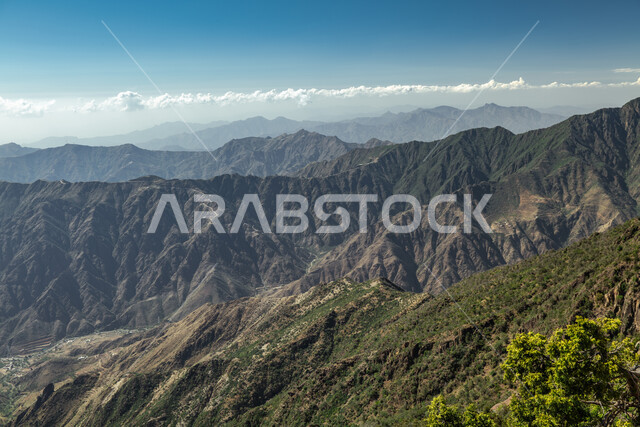 الشجر والنبات المغطي سفوح الجبل، التضاريس والبيئة الجبلية لمنطقة أبها في عسير، الطبيعة والمنتزهات والحدائق الخضراء، سلاسل الجبال الصخرية والقمم العالية في وقت النهار،  أماكن طبيعية للمغامرات ورحلات السفاري والاستمتاع