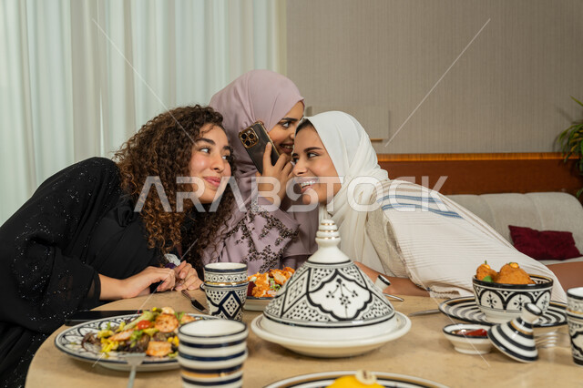 القيام بمكالمة هاتفية عبر الهاتف المحمول، ايماءات السعادة والسرور، اجتماع الرفاق على طاولة طعام في مطعم فاخر بالامارات، قضاء وقت ممتع برفقة الأصدقاء، صديقات عربيات خليجيات اماراتيات يقومون بتناول العشاء معا في الخارج، سيدات سعوديات يقومون بالإنصات الى المحادثة