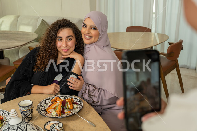 تجمع الرفاق على طاولة طعام في مطعم فاخر بالامارات، قضاء وقت ممتع برفقة الأصدقاء، التقاط صور التذكارية عبر الجوال، صديقات عربيات خليجيات اماراتيات يقومون بتناول العشاء معا في الخارج، سيدات سعوديات يستخدمون الهاتف المحمول، ايماءات السعادة والسرور