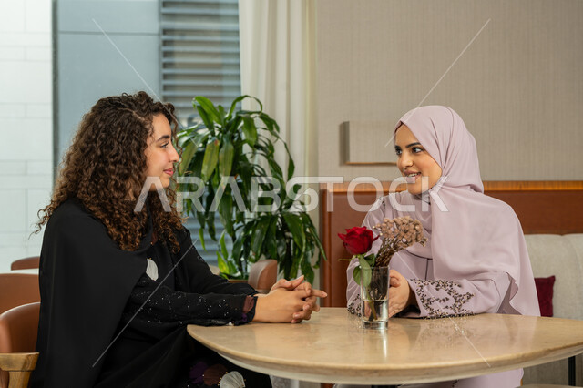 التسامر والدردشة وقضاء وقت ممتع مع الأصدقاء، جلسة وناسة يوم الاجازة، كوفي شوب راقي بالامارات، تطوير العلاقات الإجتماعية، تعابير السعادة والسرور بلمة الرفاق، امرأتين عربيتين خليجيتين اماراتيتين تجلسان على طاولة في المقهى، صديقتين سعوديتين تتبادلان الحديث