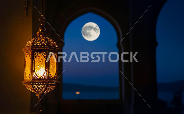 فانوس عربي تقليدي مضيء و معلق، تحف و اكسسوارات مميزة للاحتفال بقدوم شهر الخير، المصابيح المعدنية في الأجواء الرمضانية الروحانية، زينة و أنوار رمضان المبارك، خلفية السماء الصافية والقمر