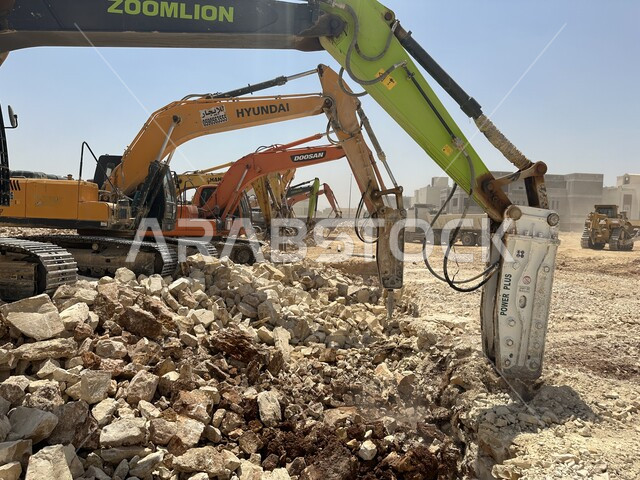 مفهوم الهندسة المعمارية والإنشاءات، جرافات ضخمة تعمل في الحفر ورفع الأنقاض والأتربة في موقع العمل، الاعتماد على الآلات والمعدات الثقيلة في أعمال البناء، مهنة ووظيفة هندسية صناعية في السعودية، تحسين البنية التحتية لإقامة المباني والمشاريع الحديثة في مدينة الرياض