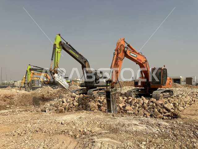 Improving the infrastructure for the construction of modern buildings and projects in the city of Riyadh, the concept of architectural and construction engineering, huge bulldozers working in digging and lifting rubble and dirt at the work site, relying on heavy machinery and equipment in construction work, an industrial engineering profession and job in Saudi Arabia