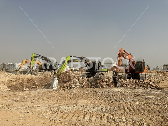 مهنة ووظيفة هندسية صناعية في السعودية، تحسين البنية التحتية لإقامة المباني والمشاريع الحديثة في مدينة الرياض، مفهوم الهندسة المعمارية والإنشاءات، جرافات ضخمة تعمل في الحفر ورفع الأنقاض والأتربة في موقع العمل، الاعتماد على الآلات والمعدات الثقيلة في أعمال البناء