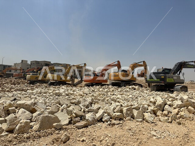 الاعتماد على الآلات والمعدات الثقيلة في أعمال البناء، وظيفة ومهنة هندسية صناعية في السعودية، تحسين البنية التحتية لإقامة المباني والمشاريع الحديثة في مدينة الرياض، مفهوم الهندسة المعمارية والإنشاءات، جرافات ضخمة تعمل في الحفر ورفع الأنقاض والأتربة في موقع العمل