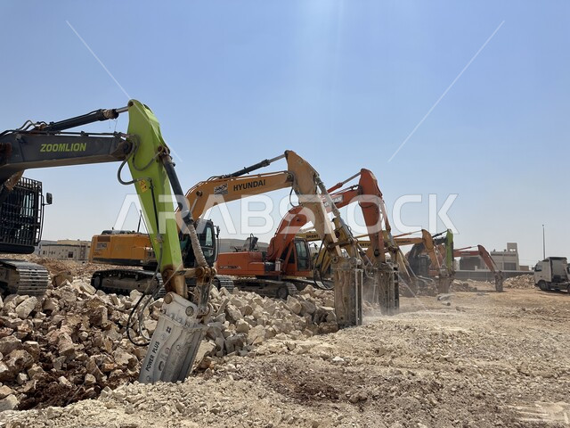 مهنة ووظيفة هندسية صناعية في السعودية، تحسين البنية التحتية لإقامة المباني والمشاريع الحديثة في مدينة الرياض، مفهوم الهندسة المعمارية والإنشاء، جرافات ضخمة تعمل في الحفر ورفع الأنقاض والأتربة في موقع العمل، الاعتماد على الآلات والمعدات الثقيلة في أعمال البناء