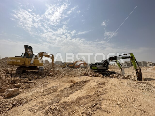الاعتماد على الآلات والمعدات الثقيلة في أعمال البناء، مهنة ووظيفة هندسية صناعية في السعودية، تحسين البنية التحتية لإقامة المباني والمشاريع الحديثة في مدينة الرياض، مفهوم الهندسة المعمارية والإنشاء، جرافات ضخمة تعمل في الحفر ورفع الأنقاض والأتربة في موقع العمل