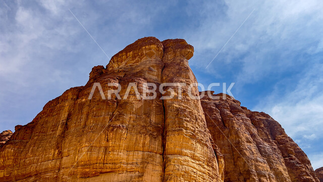 Ancient historical monuments, rock formations and mountains amidst the sandy nature during the day, natural mountain peaks and heights in the desert areas of AlUla, a famous tourist place and area in the Kingdom of Saudi Arabia