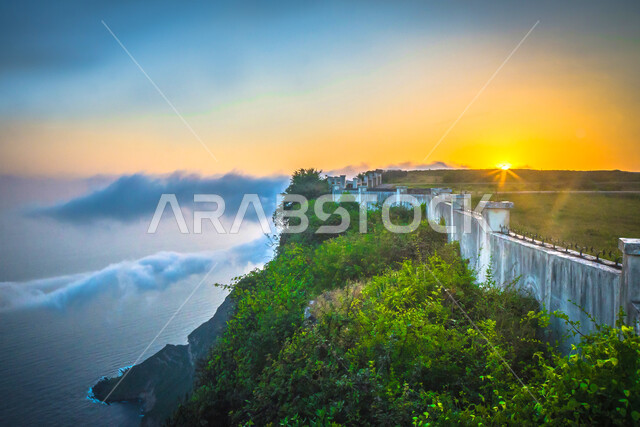 منظر غروب الشمس عند شلال مائي طبيعي بين القمم والمرتفعات الجبلية والصخرية في مدينة صلالة في محافظة ظفار، الأشجار والنباتات الخضراء، مكان ومنطقة سياحية مشهورة في دولة سلطنة عمان، مكان ترفيهي سياحي, خلفية الطبيعة