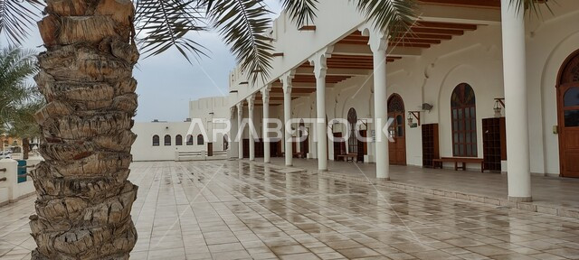 Islamic Arab architectural style of Al-Jaber Mosque in Dammam, Saudi Arabia, close-up of a palm tree trunk in the outer courtyard of the mosque, concept of worship and closeness to God Almighty, wooden doors and windows, sacred religious place and landmark