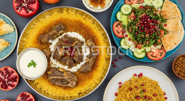 مهارة إعداد وصفة المندي الخليجي المشهورة بالتوابل الغنية بالنكهات, وصفات المأكولات والوجبات الشرقية الشهية، مطابخ ومطاعم سعودية، ولائم وأطباق عربية تقليدية شعبية، صورة علوية عامودية لطبق من أرز الكبسة مع قطع اللحم مع المقبلات، صحن من البرياني الشهير