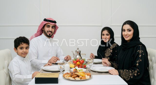 إيماءات السعادة بقدوم شهر الخير، اجتماع الأسرة حول مائدة الطعام، أداء فريضة الصيام، الاحتفال بالاعياد والمناسبات الاسلامية، بورتريه لعائله عربيه خليجيه سعوديه تجلس على سفرة افطار مليئة باصناف من المأكولات الشهية، أجواء دينية رمضانية،  جلوس عائلي على فطور رمضان، خلفية بيضاء