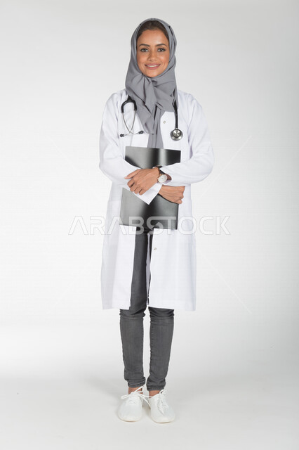 Portrait of a Saudi Arabian Gulf doctor holding a paper for a radiological examination (radiology), the concept of medicine and health care, smiling face gestures, providing health services, full body length picture, white background