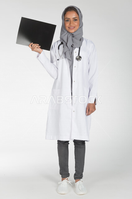 Portrait of a Saudi Arabian Gulf doctor holding a paper for a radiological examination (radiology), the concept of medicine and health care, smiling face gestures, providing health services, full body length picture, white background