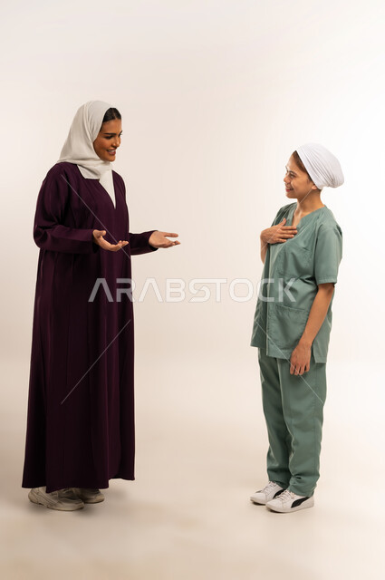 مدبرة منزل تستعين بخادمة أجنبية، توفير خدمات العناية بالمنزل، الإحسان في التعامل مع الخادمات في البيوت، استقدام العماله المنزليه المرخصه والمؤهله، بورتريه لامرأة عربية خليجية سعودية محجبة ترتدي عباءة خمرية تتحدث مع العاملة الفلبينية بتعابير الود، خلفية بيضاء