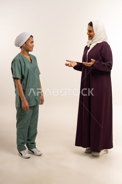 الإحسان في التعامل مع الخادمات في البيوت، توفير خدمات العناية بالمنزل، استقدام العماله المنزليه المرخصه والمؤهله، بورتريه لامرأة عربية خليجية سعودية محجبة ترتدي عباء خمرية تتحدث مع العاملة الفلبينية بتعابير الود، مدبرة منزل تستعين بخادمة أجنبية، خلفية بيضاء