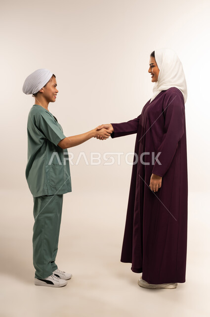 استئجار العماله المنزليه المرخصه والمؤهله، توفير خدمات العناية بالمنزل، بورتريه لإمرأة عربية خليجية سعودية محجبة ترتدي عباءة خمرية تصافح عاملة نظافة فلبينية، الترحيب بالعاملات والخادمات من الشركات السعوديه، مهن ووظائف نسائية، الطول الكامل للجسم، خلفية بيضاء