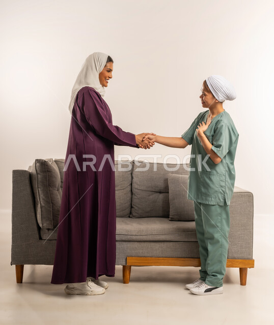 توفير خدمات العناية بالمنزل، استئجار العماله المنزليه المرخصه والمؤهله، بورتريه لإمرأة عربية خليجية سعودية محجبة ترتدي عباءة خمرية تصافح عاملة نظافة فلبينية، الترحيب بالعاملات والخادمات من الشركات السعوديه، مهن ووظائف نسائية، الطول الكامل للجسم، خلفية بيضاء