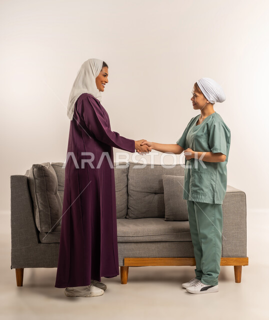 استئجار العماله المنزليه المرخصه والمؤهله، توفير خدمات العناية بالمنزل، بورتريه لإمرأة عربية خليجية سعودية محجبة ترتدي عباءة خمرية تصافح عاملة نظافة فلبينية، الترحيب بالعاملات والخادمات من الشركات السعوديه، مهن ووظائف نسائية، الطول الكامل للجسم، خلفية بيضاء