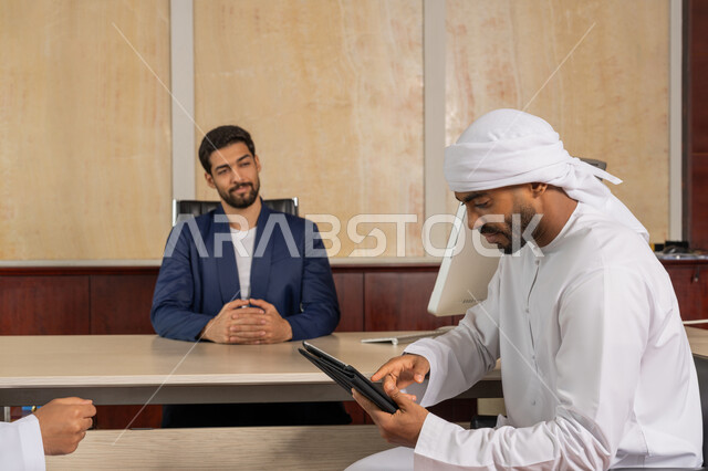 الوحدة والعمل الجماعي لتطوير العمل وحل المشكلات، مناقشة مهام العمل باستخدام التابليت، تحقيق اهداف الشركة، مكاتب و شركات خليجية، رجل اعمال يرتدي البدلة الرسمية يجلس في المكتب مع زميله, مفهوم الإدارة المتعاونة، مهنة ووظيفة اماراتية