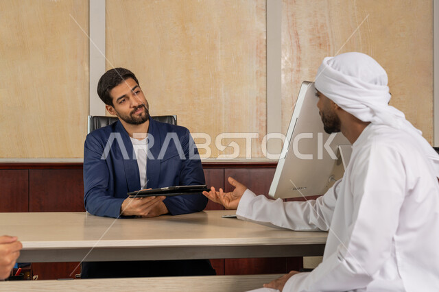 مناقشة مهام العمل باستخدام التابليت، تحقيق اهداف الشركة، مكاتب و شركات خليجية، الوحدة والعمل الجماعي لتطوير العمل وحل المشكلات، رجل اعمال يرتدي البدلة الرسمية يجلس في المكتب مع زميله, مفهوم الإدارة المتعاونة، مهنة ووظيفة اماراتية
