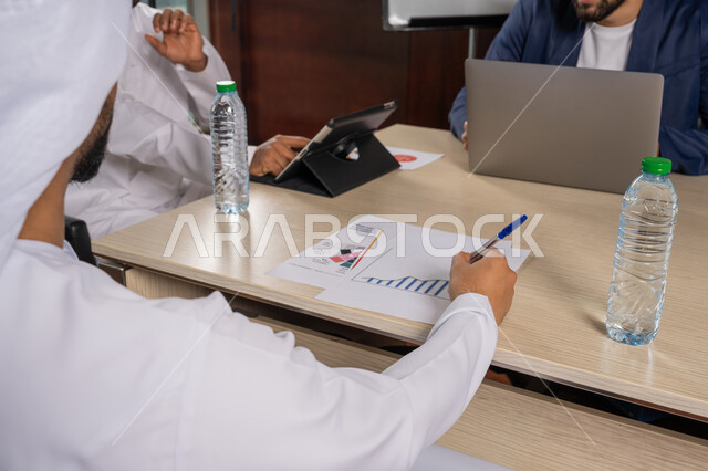 مراجعة التقرير السنوي، دراسة ومناقشة سير استراتيجية العمل، استخدام التقنية الحديثة المتطورة، صور مقربة لرجلان عربيان اماراتيان خليجيان يرتديان الكندورة مع رجل بالبدلة الرسمية يجلسون في المكتب داخل مقر الشركة, الاتفاق على المشروع التجاري، مهنة ووظيفة اماراتية