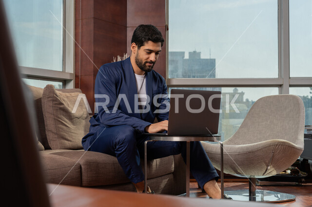 استخدام التقنيات الحديثة المتطورة، جلسه عمل عن بعد, أداء المهمة اليومية داخل مقر الشركه، رجل أعمال عربي خليجي اماراتي يرتدي الزي الرسمي يقوم بالعمل على جهاز الحاسوب المحمول، دراسه المشروع ومراجعه التقرير السنوي، دمج التقنية والتكنولوجيا في الحياة العملية