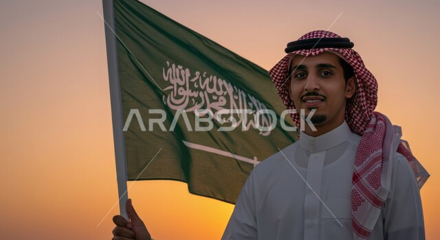 إظهار الحب والولاء للدولة في اليوم الوطني 23 سبتمبر,  حب الوطن والانتماء إليه, يوم العلم 11 مارس, صورة مقربة لرجل عربي سعودي خليجي يرتدي الثوب والشماغ ويضع العلم على كتفه وقت غروب الشمس, خلفية أبراج الرياض