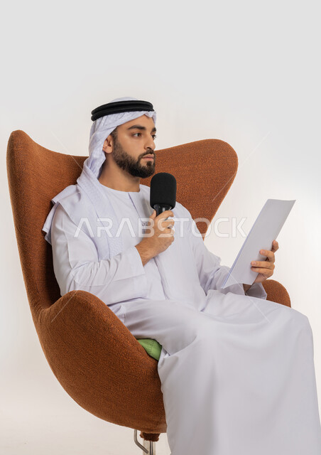 التواصل الفعال وتبادل الحوار والنقاش، القاء الخطابات من الورقة بإيماءات الثقة بالنفس، تقديم ورش العمل والدورات التدريبية، فن التحدث والخطابة، بورتريه لشاب عربي خليجي اماراتي يرتدي الكندورة والغترة يجلس على الكرسي يمسك مكبر الصوت، خلفية بيضاء