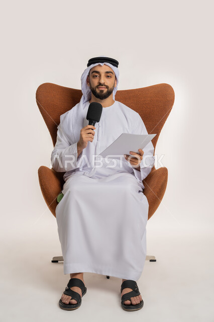 تبادل الحوار والنقاش والتواصل الفعال، القاء الخطابات من الورقة بإيماءات الثقة بالنفس، تقديم ورش العمل والدورات التدريبية، فن التحدث والخطابة، بورتريه لشاب عربي خليجي اماراتي يرتدي الكندورة والغترة يجلس على الكرسي يمسك مكبر الصوت، خلفية بيضاء