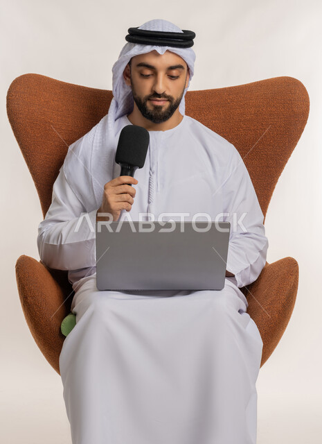 اجراء مقابلة شخصية، النقاش والتواصل الفعال، فن الالقاء والخطابة، دورة تدريبية اونلاين، بورتريه لشاب عربي خليجي اماراتي يرتدي الكندورة والغترة يمسك مكبر الصوت يجلس على الكرسي يقوم بالقراءة من الحاسب المحمول، إلقاء الخطاب بإيماءات الثقة بالنفس، خلفية بيضاء