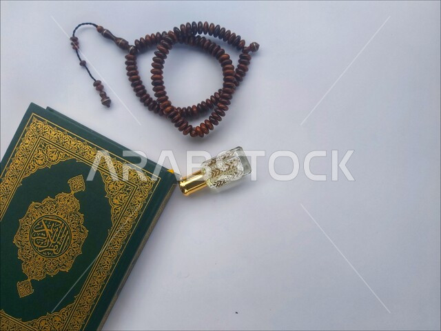مفهوم التطيب والتعطر، الاجتهاد في الدعاء وطلب المغفرة, الاكثار من الاذكار في شهر رمضان المبارك، التعبد بتلاوة القران وحفظ وتفسير كلامه، صورة مقربة للمصحف الشريف مع سبحة وعطر، الجو الديني الروحاني, العبادة والتقرب إلى رب العالمين، خلفية بيضاء