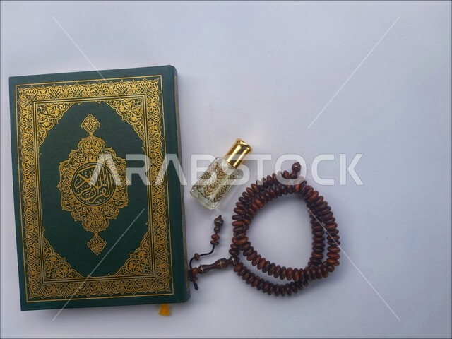 الاجتهاد في الدعاء وطلب المغفرة, الاكثار من الاذكار في شهر رمضان المبارك، التعبد بتلاوة القران وحفظ وتفسير كلامه، صورة مقربة للمصحف الشريف مع سبحة وعطر، الجو الديني الروحاني, العبادة والتقرب إلى رب العالمين، مفهوم التطيب والتعطر، خلفية بيضاء