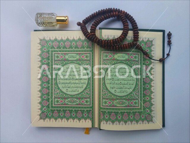 التعبد بتلاوة القران وحفظ وتفسير كلامه، الاجتهاد في الدعاء وطلب المغفرة, الاكثار من الاذكار في شهر رمضان المبارك، صورة مقربة للمصحف الشريف مع سبحة وعطر، الجو الديني الروحاني, العبادة والتقرب إلى رب العالمين، مفهوم التطيب والتعطر، خلفية بيضاء