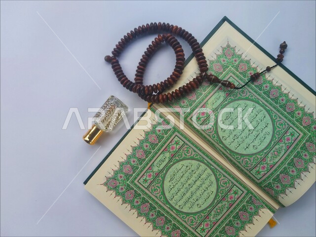 الاجتهاد في الدعاء وطلب المغفرة, الاكثار من الاذكار في شهر رمضان المبارك، التعبد بتلاوة القران وحفظ وتفسير كلامه، صورة مقربة للمصحف الشريف مع سبحة وعطر، الجو الديني الروحاني, العبادة والتقرب إلى رب العالمين، مفهوم التطيب والتعطر، خلفية بيضاء