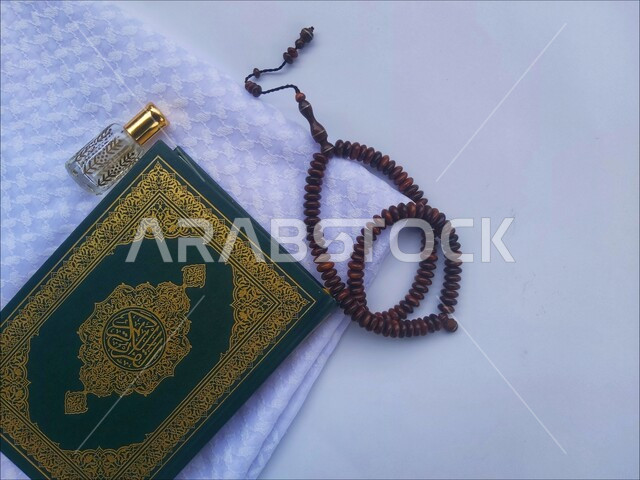 التعبد بتلاوة القران وحفظ وتفسير كلامه، الاجتهاد في الدعاء وطلب المغفرة, الاكثار من الاذكار في شهر رمضان المبارك، صورة مقربة للمصحف الشريف مع سبحة وعطر، الجو الديني الروحاني, العبادة والتقرب إلى رب العالمين، مفهوم التطيب والتعطر، خلفية بيضاء