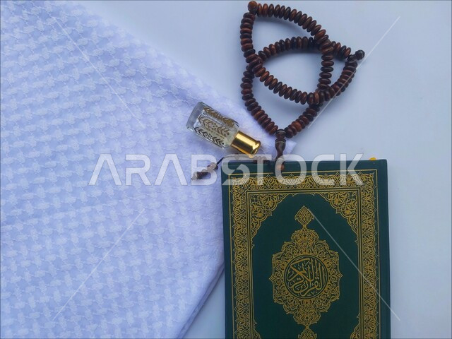 مفهوم التطيب والتعطر، الاجتهاد في الدعاء وطلب المغفرة, الاكثار من الاذكار في شهر رمضان المبارك، التعبد بتلاوة القران وحفظ وتفسير كلامه، صورة مقربة للمصحف الشريف مع سبحة وعطر، الجو الديني الروحاني, العبادة والتقرب إلى رب العالمين، خلفية بيضاء