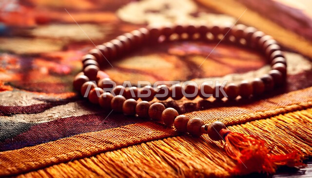 مفهوم التسبيح والتهليل، الاجتهاد في العبادة والتقرب إلى رب العالمين في شهر رمضان المبارك, صورة مقربة لسبحة على سجادة الصلاة, الإكثار من ذكر الله تعالى من خلال الاستغفار والدعاء، الالتزام بالأذكار اليومية