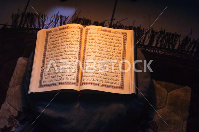 التعبد بتلاوة القران وحفظ وتفسير كلامه في رمضان المبارك، صورة من الاعلى للمصحف الشريف مفتوح على وسادة مع سجادة الصلاة، مفهوم العبادة والتقرب إلى الله في الأيام الفضيلة
