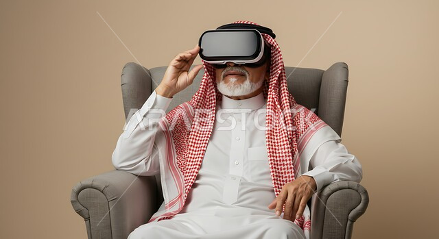إيماءات الاندماج والتركيز، استخدام جهاز تقني حديث، المتعة والتسلية بالمشاهدة عبر نظارة الواقع الافتراضي، بورتريه لرجل عربي خليجي سعودي كبير بالسن يرتدي الثوب التقليدي والشماغ يجلس على كرسي مريح ينظر من خلال نظارات ثلاثية الأبعاد، محاكاة العالم الخيالي، خلفيه بيج