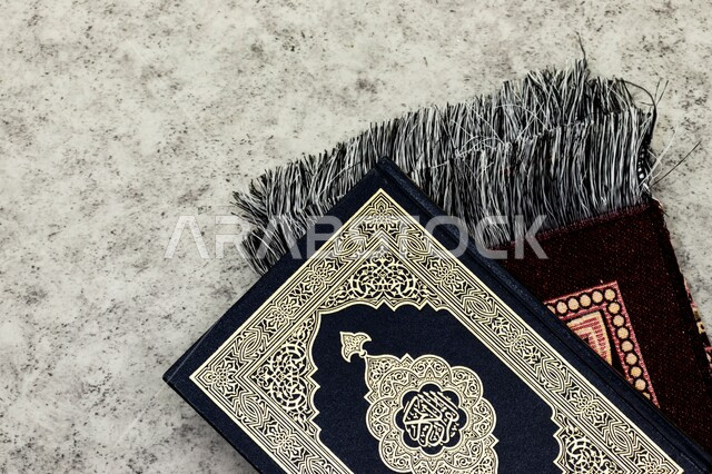 أداء فريضة الصلاة على وقتها، الجو الديني الروحاني, الاجتهاد في الدعاء وطلب المغفرة في شهر رمضان المبارك، العبادة والتقرب إلى رب العالمين، التعبد بتلاوة القران وحفظ وتفسير كلامه، صورة مقربة للمصحف الشريف مع سجادة