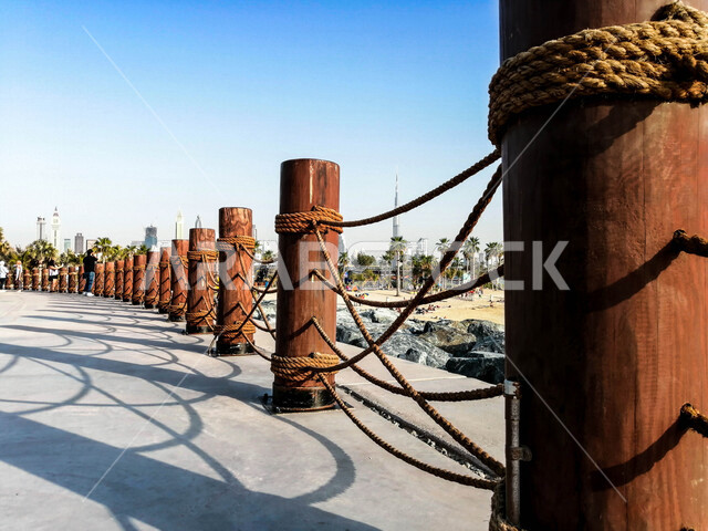 صورة لممر محاط باعمدة خشبية بجانب شاطئ دبي ، جمال الاماكن السياحية الطبيعية في الامارات العربية المتحدة