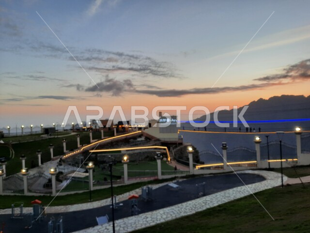 منظر طبيعي متميز في منتزه بالمملكة العربية السعودية، الاهتمام بزراعة النباتات الخضراء في المنتزهات والحدائق العامة المضيئة وقت الغروب، الجسر الخشبي المعلق في حديقة الأمير حسام في محافظة الباحة، معلم سياحي مشهور، مكان جذب واستقطاب السائحين