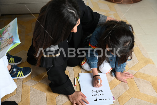 طفلان عربيان خليجيان سعوديان مستمتعان باللعب مع والديهما، الرسم على الورق ، قراءة قصص وروايات ، عائلة عربية خليجية سعودية مبتسمة وسعيدة ،تنمية قدرات و مهارات الطفل ، اجواء عائلية سعيدة