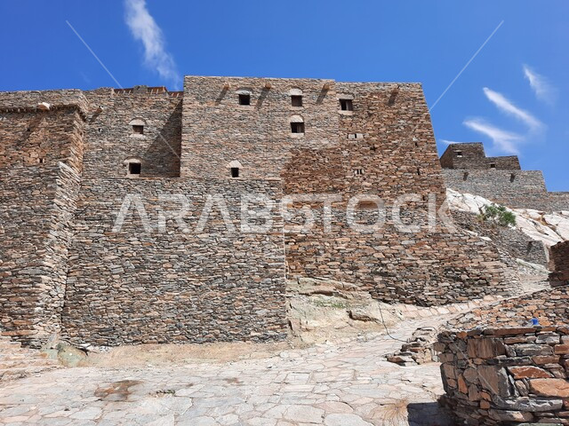 Ancient archaeological building made of stones and trunks of Sidr trees, the historic and fortified marble village of Dhi Ain, the architectural design of houses and buildings in villages in the Kingdom of Saudi Arabia, a famous tourist mountain landmark