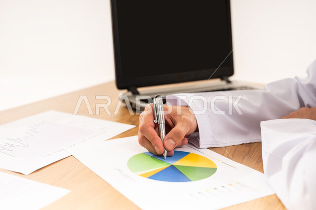 Business strategy development and growth plan, monitoring economy and financial information, financial and economic investment, close-up side portrait of an Arab Gulf Omani man in traditional dress sitting in front of a wooden table studying and analyzing data, company profit and loss data, white background