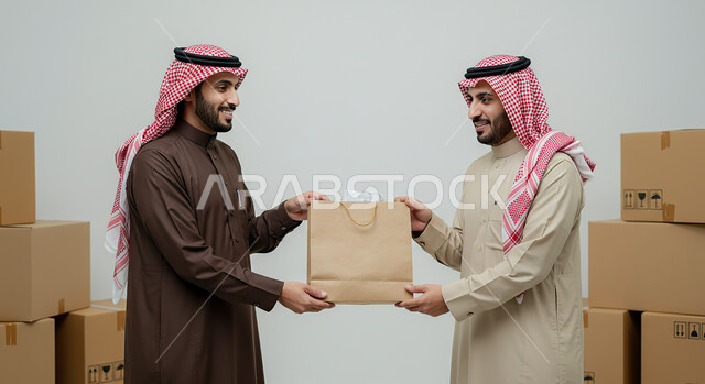 Express delivery services, e-shopping concept, reliance on online purchases, ordering products online, portrait of a Saudi Arabian Gulf man wearing traditional thobe and shemagh taking a paper bag from the delivery man, delivering orders to customers easily and quickly, white background